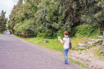 Tourist with map getting around ancient ruins in Rome old town, Appia Antica way, heritage of early italian history, travel destination for tourists. Toned image.