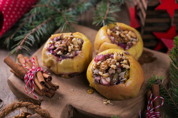 Baked apples stuffed with berries, walnuts and honey on a wooden cutting board.
