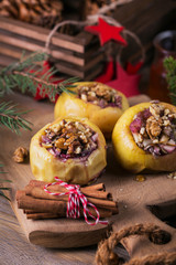 Baked apples stuffed with berries, walnuts and honey on a wooden cutting board.