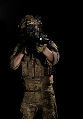 Army soldier in Combat Uniform with assault rifle, combat helmet and night vision device. Studio shot, dark background