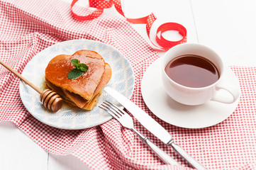 Fototapeta na wymiar heart shaped pancakes on a light background. the concept of a festive breakfast for Valentine's Day or a pleasant surprise for a loved one