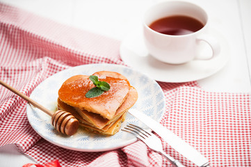heart shaped pancakes on a light background. the concept of a festive breakfast for Valentine's Day or a pleasant surprise for a loved one