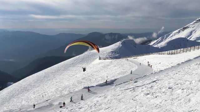 paraglider flying among snowy peaks in a ski resort in the Caucasus mountains