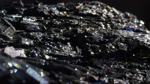 MACRO CLOSE UP: Shimmering dark Hematite with a metallic surface. Mineral form of iron oxide with intense sparkling detail. Radiant piece of haematite known for its earthy energy and use in feng shui