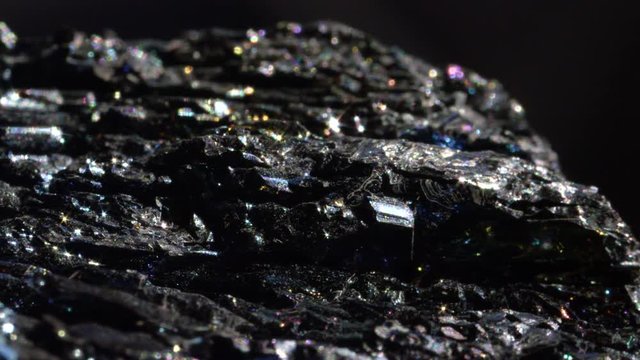 CLOSE UP BOKEH: Shimmering dark Hematite with a metallic surface. Mineral form of iron oxide with intense sparkling detail. Radiant piece of haematite known for its earthy energy and use in feng shui