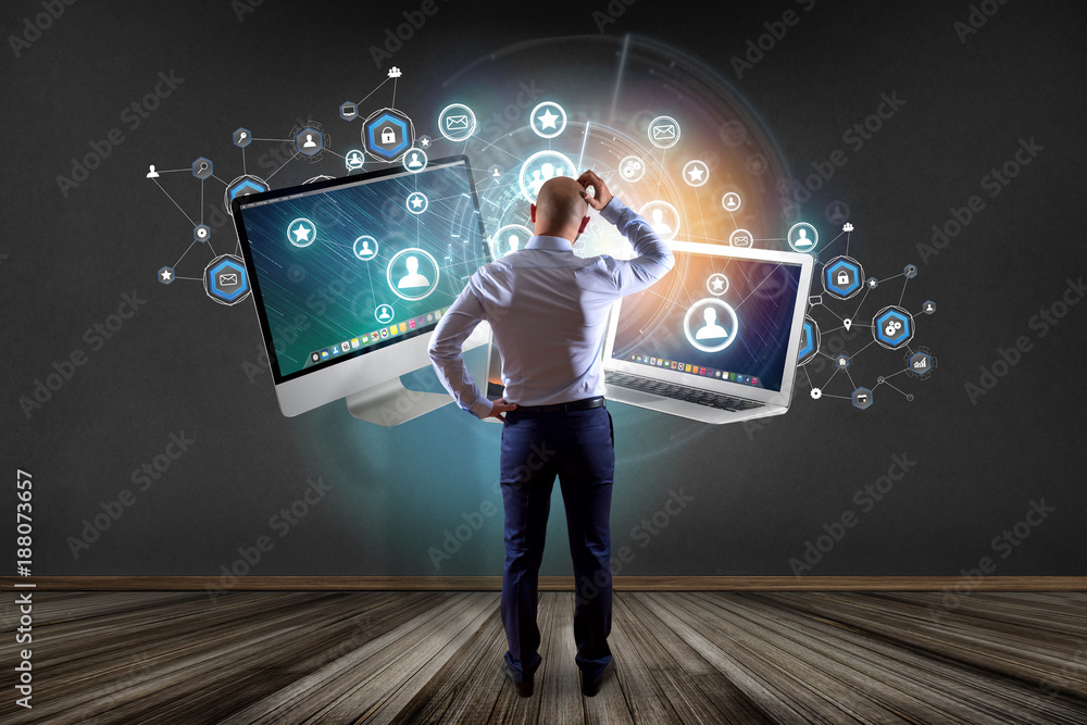Poster businessman in front of a wall with computer and devices displayed on a futuristic interface with bu