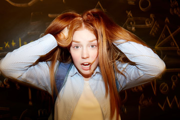 Ginger head girl ruffling her long hair with confused expression