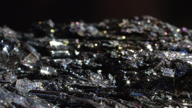 MACRO CLOSE UP: Black Hematite sparkling in variety of colors. Mineral known as blood stone after it's processed reveals its glowing and metallic sheen. Inexpensive iron oxide shimmering under light
