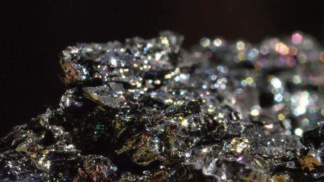 MACRO BOKEH: Black Hematite with intense metallic finish glimmering under light. Mineral form of iron oxide after being processed revealing its glistening surface. Stunning dark brittle gem sparkling