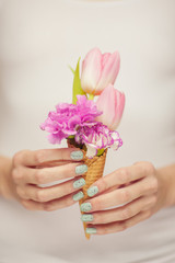 woman hands holding spring flowers in an ice cream cone, sensual studio shot can be used as background