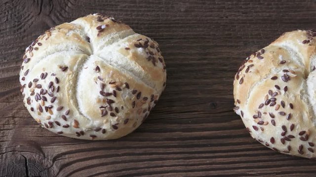 Tasty freshly baked kaiser rolls with seeds on wooden board
