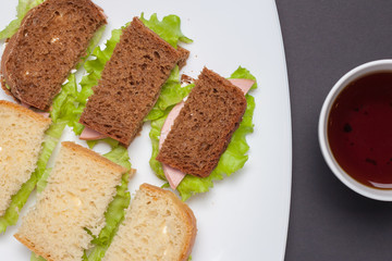 Mug of tea next to a plate of sandwiches. Breakfast student