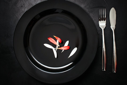 Single Plate With Fork And Knife On Black Background. Dinner For One. Sarcastic Weight Loss Diet Concept