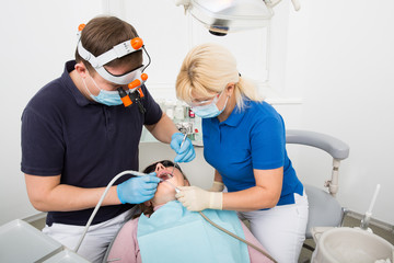 Dentist in scrubs googles and mask at work. female patient visiting dentist office. dentist and...