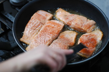  large steak of salmon is fried in sunflower oil.