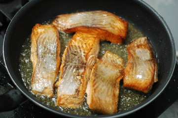  large steak of salmon is fried in sunflower oil.
