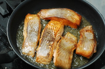 large steak of salmon is fried in sunflower oil.