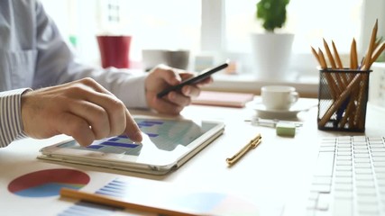 Businessman works with a tablet computer and studies financial information. Close view and very smooth dolly shot. 4K video with shallow depth of field focus on hands. - Powered by Adobe