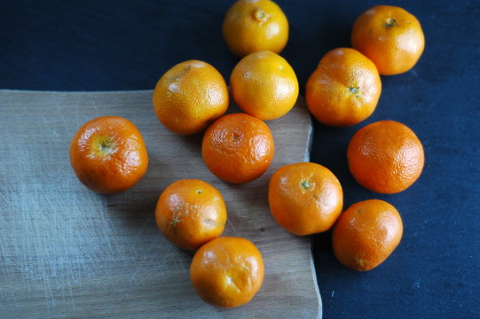 Unpeeled mandarins on a dark background with hard light.