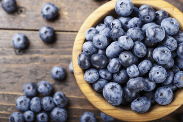 ripe organic bog whortleberry in a wooden plate on a wooden background