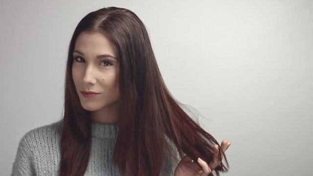 spanish woman touching her straight hair and looking at camera