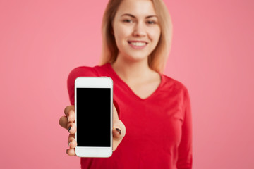 Cropped shot of beautiful woman holds modern cell phone in hands, blank copy space for your advertisment or promotional text. Focuse on mobile phone. Modern technologies and communication concept