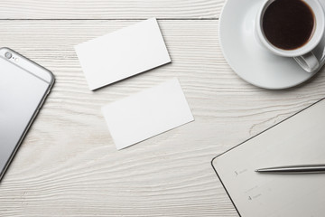 Cup of coffee, book, notepad and pen on white wooden desk