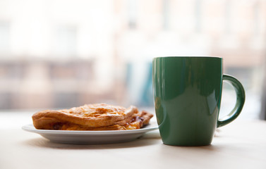 cup with a drink and puff pastries in the morning on a table in a cafe