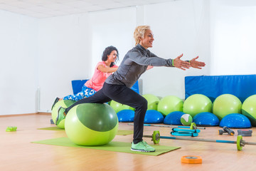Fototapeta premium Active middle-aged woman working out with stability ball taking part in group fitness class