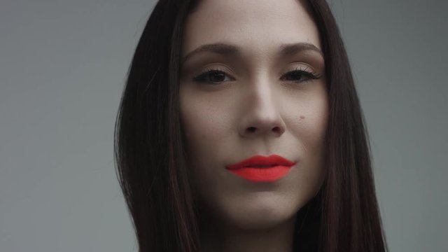 closeup of spanish woman with vivid orange matte lipstick in studio. Straight hair and ideal skin