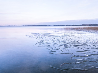 Low aerial view of a lake coast that has been lightly frozen on a winter day. Tartu, Estonia.