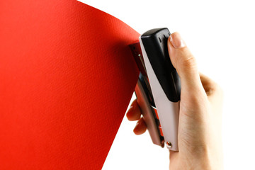 Fasten the red paper with staples on a white background. Closeup