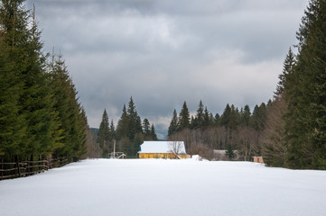 Yellow house in winter forest. Forest ranger house among deep snowdrifts in the forest.