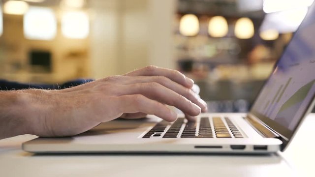 Business man working over computer in modern office male typing fingers hand on a laptop keyboard creates a project presentation using digital display technology. Business people working on device
