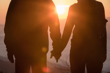 Couples holding hands.Summer in love,Young couple Love couple silhouette looking sunrise in mountains.