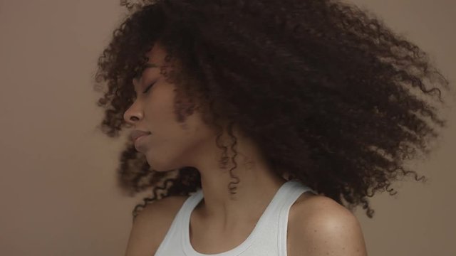 black model with huge curly hair moving shaking hair in slow motion from 60 fps studio shoot