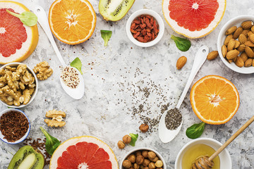 Ingredients of healthy dietary food breakfast pink grapefruit, orange, chia seeds, quinoa, green herbs, kiwi, wild rice, almonds, walnuts, hazelnuts on a light marble background. The concept of
