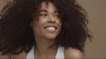 happy laughing black woman with wind moving her cyrly hair in sytdio - Powered by Adobe