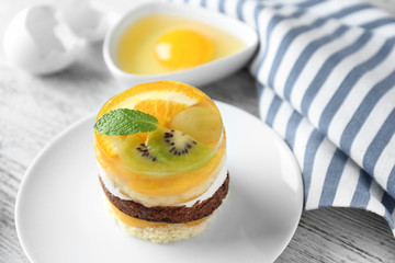 Plate with tasty fruit sponge cake on table