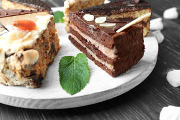 Pieces of tasty cakes on wooden board