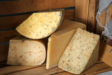 Different kinds of delicious cheese in wooden crate