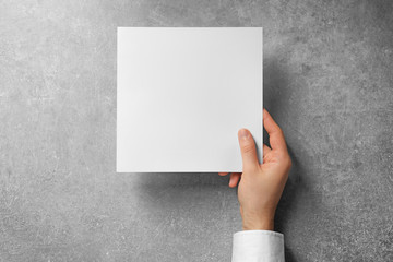 Man holding blank sheet of paper on grey background. Mock up for design