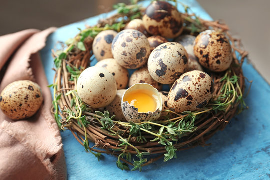 Raw quail eggs in nest on wooden table