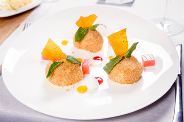 Plum dumplings with cinnamon, white chocolate and vanilla sauce served in a restaurant