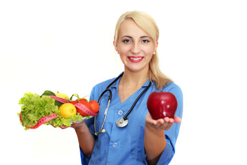 Beautiful female doctor a dietician holds a red apple and a plate of fresh fruits and vegetables isolated on a white background