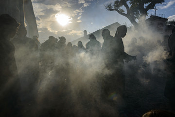 Antigua, Guatemala - April 19, 2014: Silhouette of men wearing black robes and hoods spreading incense in a street of the city of Antigua during a procession of the Holy Week in Antigua, Guatemala