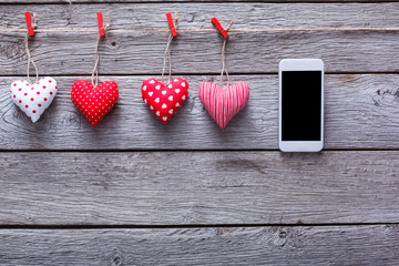 Valentine day background, pillow hearts and smartphone on wood