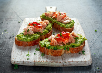 Homemade Toast sandwich with Salmon, Avocado and chilli jam on wihte wooden board. healthy food
