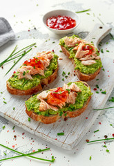 Homemade Toast sandwich with Salmon, Avocado and chilli jam on wihte wooden board. healthy food