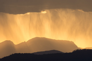 Setting sun behind a rain shower near Lijiang in Yunnan, China
